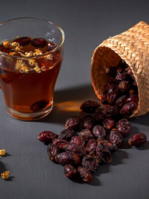 Herbal tea with medical chamomile and dried rosehips on a dark table
