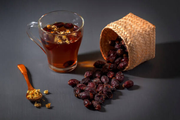 Herbal tea with medical chamomile and dried rosehips on a dark table