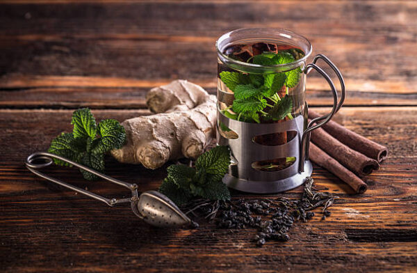 Cup of herbal tea with fresh mint on wooden table