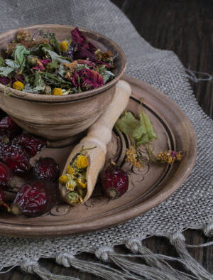 Herbal tea ingredients with hip roses, chamomile, herbs on wooden table