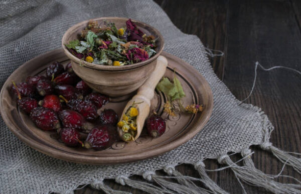 Herbal tea ingredients with hip roses, chamomile, herbs on wooden table
